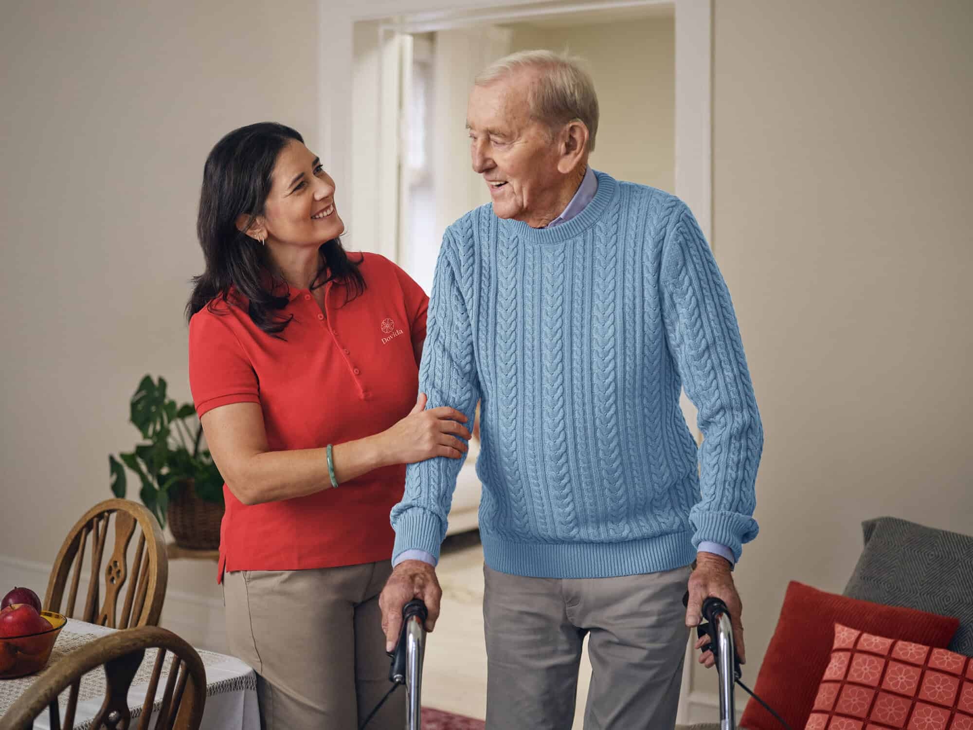 Dovida Caregiver supporting elderly man using a walker at home.
